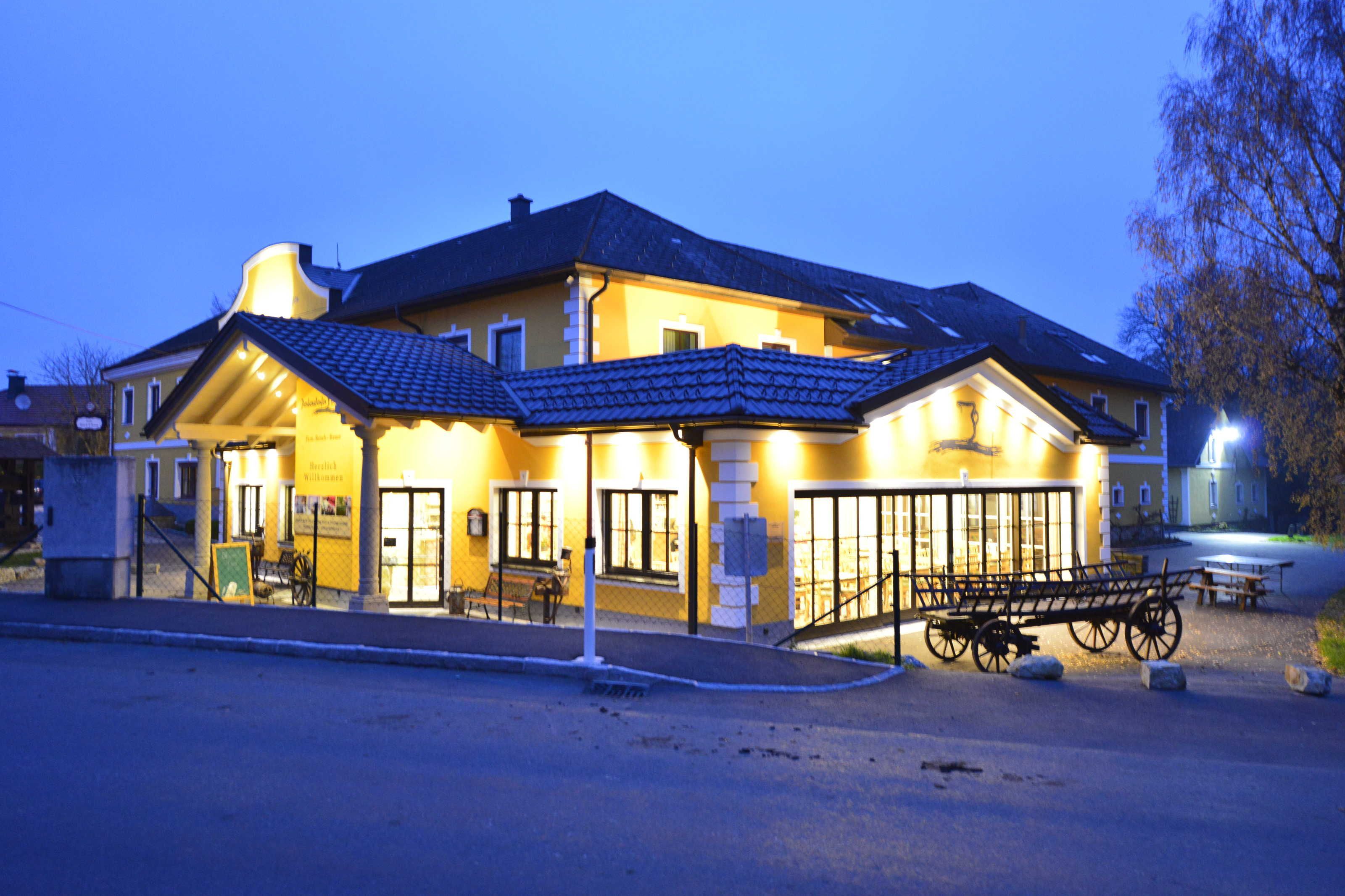 Ein Gebäude mit gelber Fassade, einem überdachten Eingang und einer Bank davor.