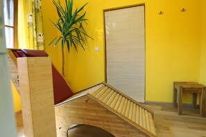 Une pièce avec un banc en bois, une plante en pot, une porte coulissante et une petite table.