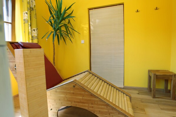 A room with a wooden bench, a potted plant, a sliding door, and a small table.