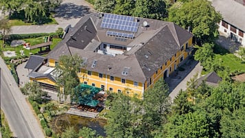 A yellow building with solar panels, a pond, and a small bridge.