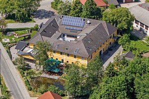 A yellow building with solar panels, a pond, and a small bridge.
