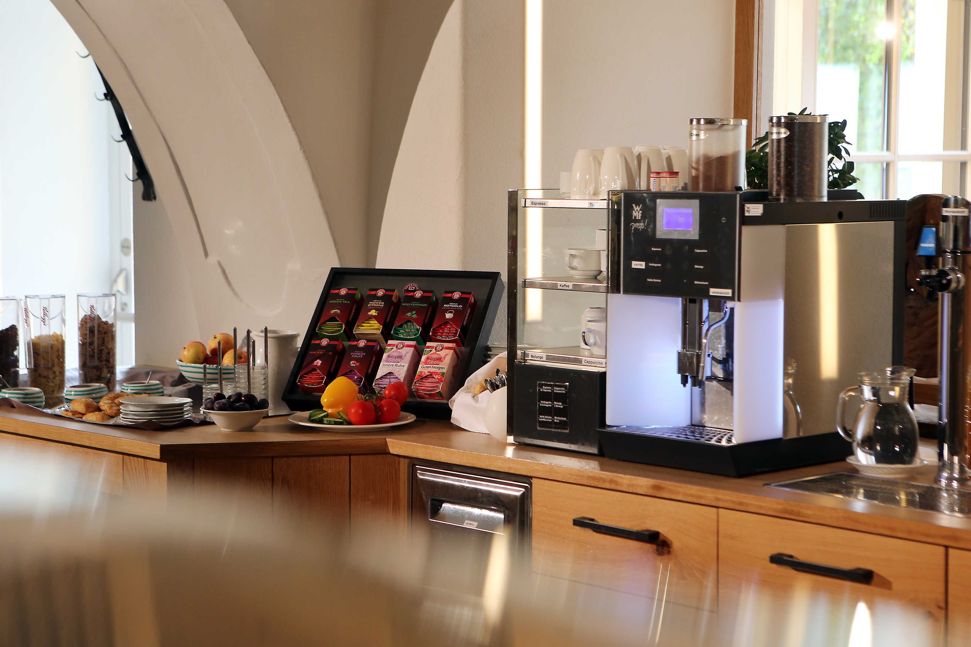 A coffee station with a coffee machine, cups, and a variety of coffee pods.