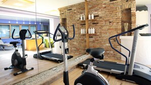 Un gimnasio con equipo de ejercicio, una pared de ladrillo y piso de madera.