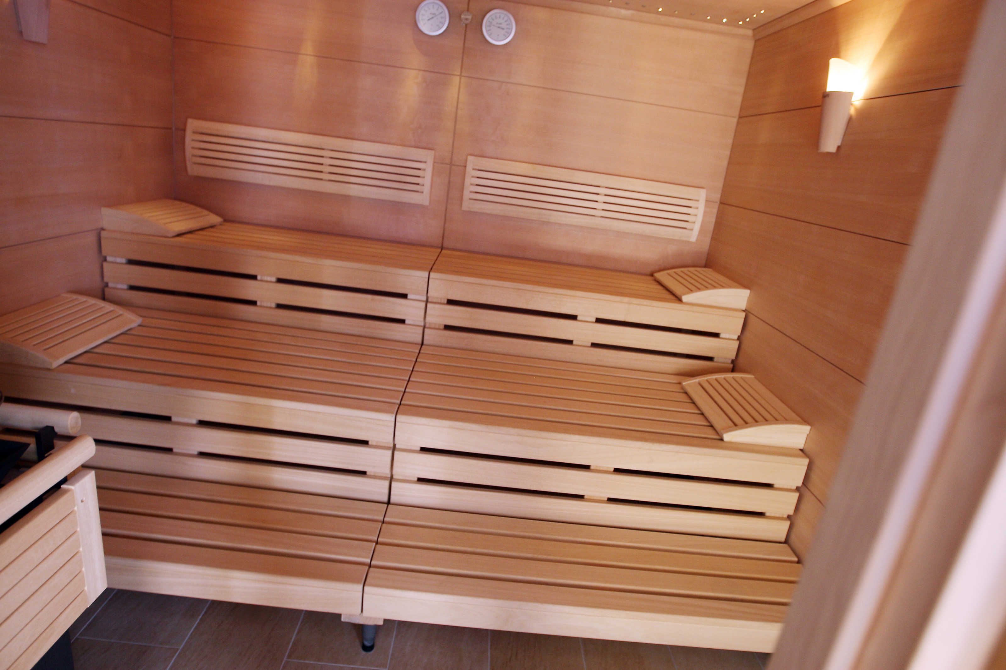 Un sauna avec des bancs en bois, des radiateurs fixés au mur et une horloge murale.
