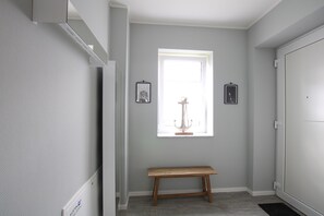 A hallway with a bench, a window with natural light, and framed pictures on the wall. - Sonnengarten 3 - KüstenART (Kellenhusen)
