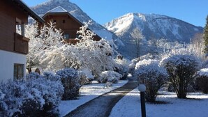 A snow-covered pathway leading to a wooden building with a mountain backdrop. - Gutshof Wolfgangsee Resort & Event Hotel (Strobl)