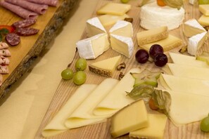 A variety of cheeses and cured meats on a wooden board. - Gutshof Wolfgangsee Resort & Event Hotel (Strobl)