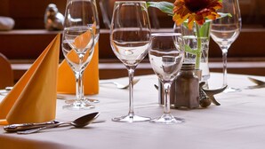 A table set with wine glasses, a flower, and a deer figurine. - Gutshof Wolfgangsee Resort & Event Hotel (Strobl)