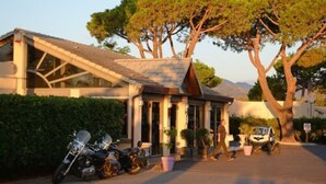 A modern building with a sloped roof, columns, and a paved driveway. - Residence San Pellegrino (Penta-di-Casinca)