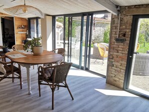 A dining area with a round wooden table, wicker chairs, and a potted plant. - Stone House for 6 in Le Bernard, 6.5 km from Beaches (Le Bernard)