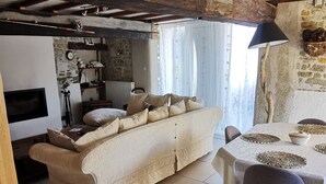 A cozy living room with a sofa, a dining table with chairs, and a lamp.