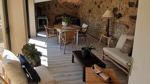 A cozy living room with a stone wall, wooden furniture, and a dining area with a table and chairs.