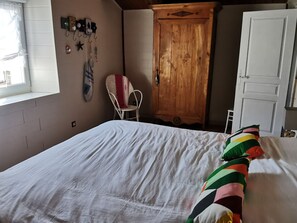 Un dormitorio con cama, un armario de madera, una silla y una ventana.