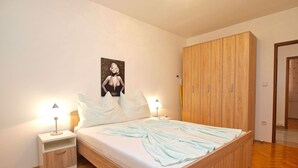 A bedroom with a wooden bed, two bedside tables, a wardrobe, and a poster on the wall. - Apartment 1424/13309 (Istria - Pula), 2500m from the beach (Pula)
