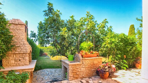 A patio area with a stone-tiled floor, a brick structure, and potted plants. - Apartment 1424/13309 (Istria - Pula), 2500m from the beach (Pula)