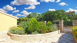 A courtyard with a stone wall, a tiled floor, and various plants. - Apartment 1424/13309 (Istria - Pula), 2500m from the beach (Pula)