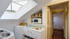 Una cocina compacta con tragaluz, microondas y un refrigerador pequeño.