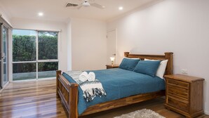 A bedroom with a wooden bed, a nightstand, a dresser, and a large window. - Burnvale: spacious family home, 500m to beach, air-conditioned (Dunsborough)