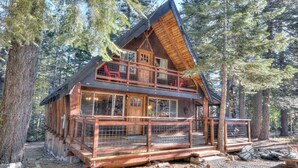 A two-story log cabin with a balcony, surrounded by trees. - Enchanting Chamberlands Cabin (Tahoma)