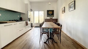 A modern kitchen with white cabinets, a wooden dining table, and a view to the outdoors.