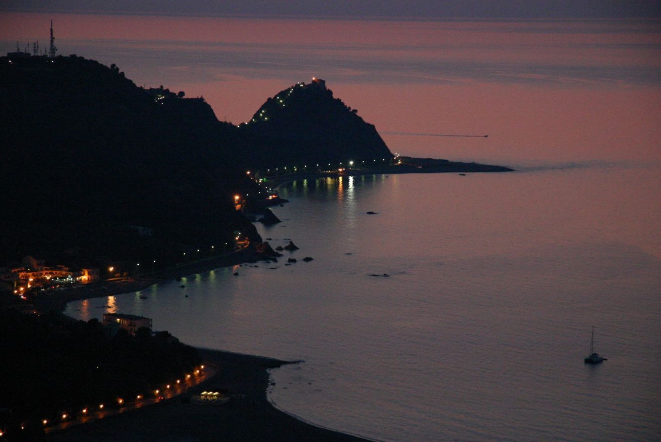 A coastal scene with a prominent hill and a calm sea.