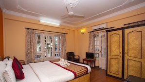 Habitación de hotel con una cama grande, televisión, escritorio y armario.