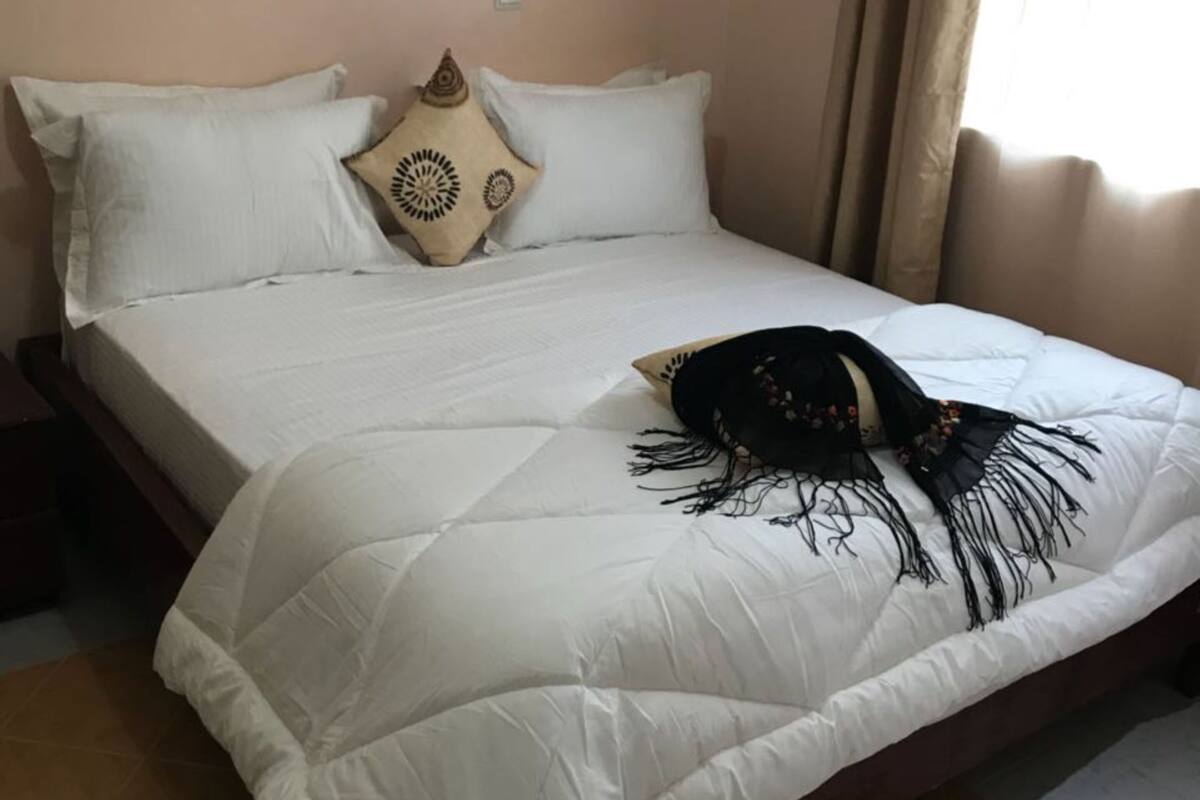 A bed with white bedding and a decorative black headboard.