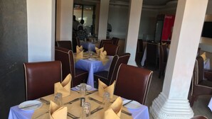 A restaurant with tables set for dining, featuring a modern interior with white columns and blue tablecloths. - Villa Rosa Mystica Hotel (Homa Bay)