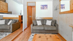 Un salon chaleureux avec deux canapés gris, une table basse en bois et un tapis à motifs.