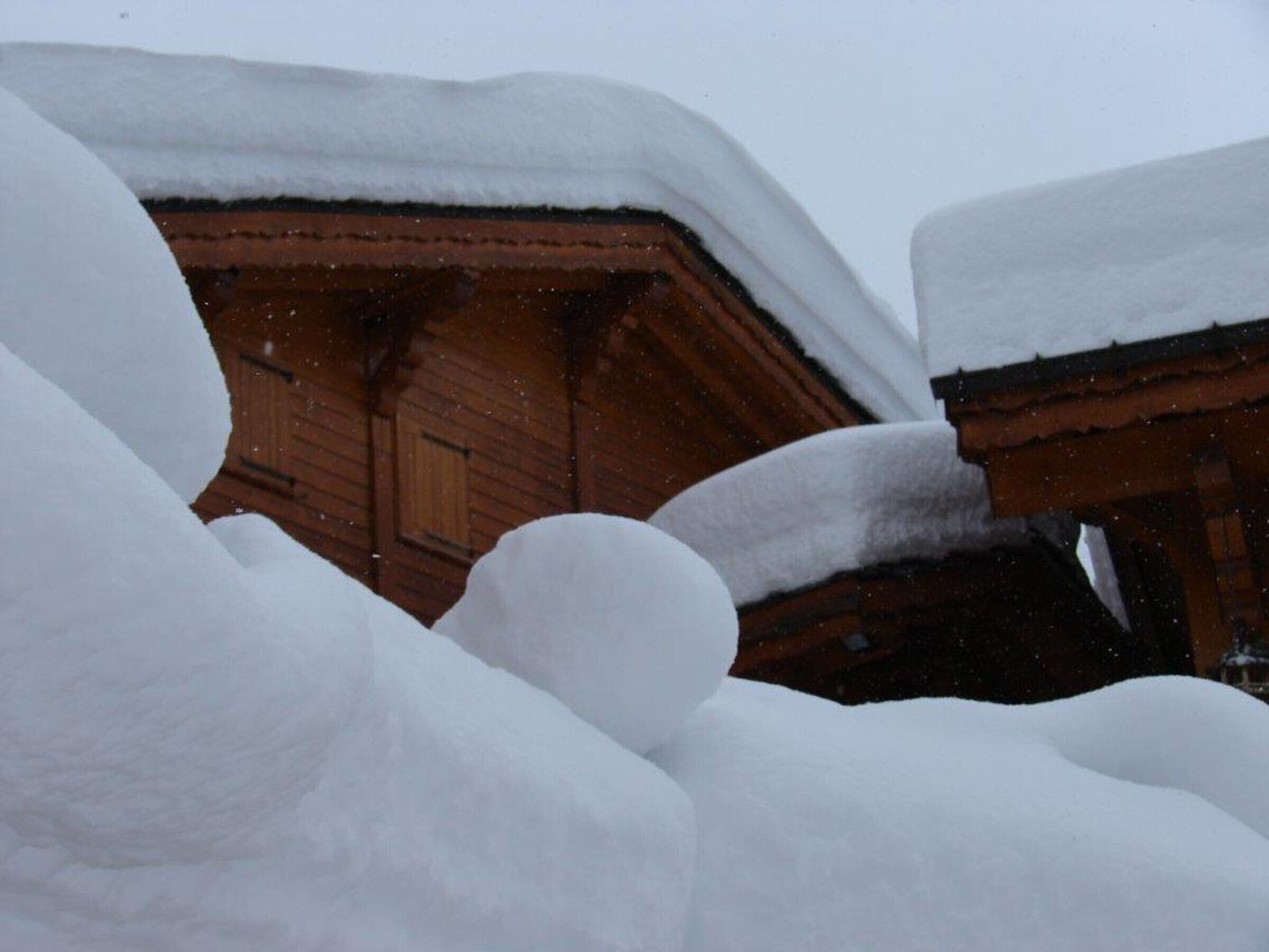 Une cabane en bois partiellement recouverte de neige.