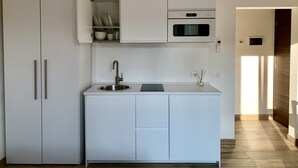 Una cocina moderna con armarios blancos, un lavamanos de acero inoxidable y un horno empotrado.