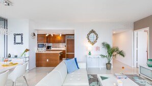 A modern living room with a sofa, dining table, and a kitchen in the background.