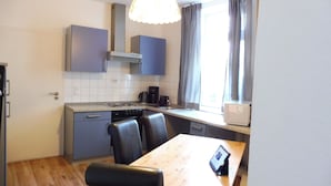 A compact kitchen with grey cabinets, a wooden dining table, and a built-in oven. - Living in the historic imperial building (Wismar)