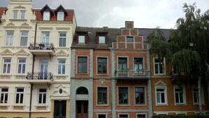 A row of multi-story residential buildings with distinct architectural styles, featuring balconies and large windows. - Living in the historic imperial building (Wismar)