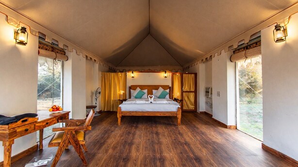 Une chambre à coucher avec un lit en bois, un bureau et une chaise, une fenêtre avec des rideaux et un plafond orné d’un motif triangulaire.