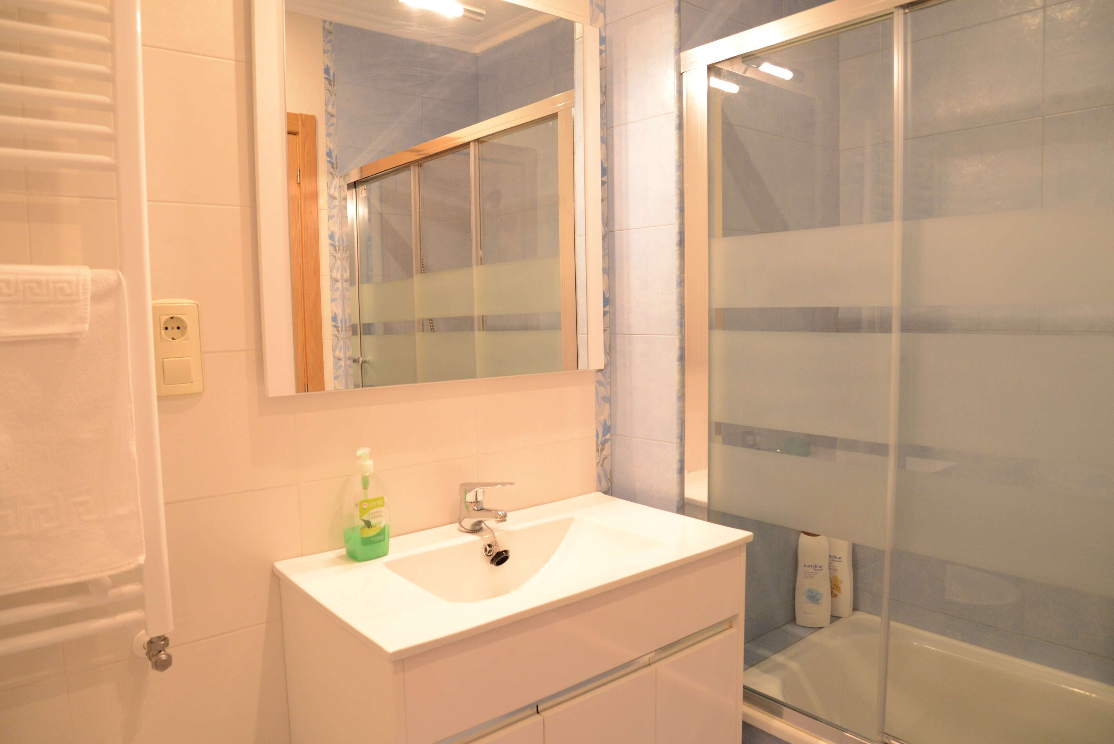 A bathroom with a white sink, a mirror, and a glass shower enclosure.
