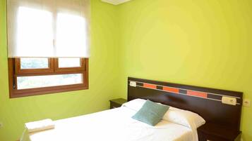 Een kamer met een bed, een nachtkastje, een raam met jaloezieën en een wand met een structuur.