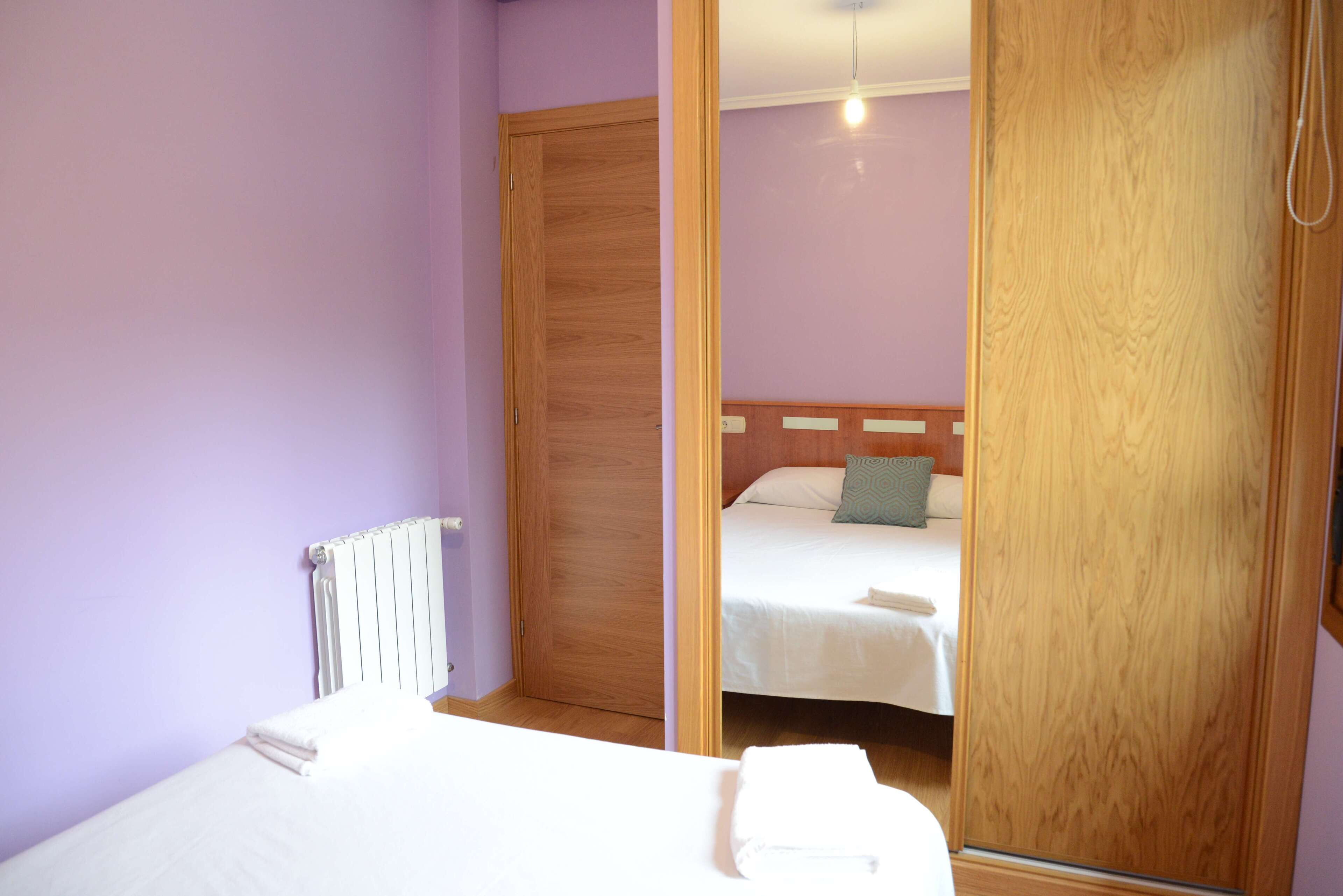 Une chambre à coucher avec un lit, une armoire en bois et un radiateur.