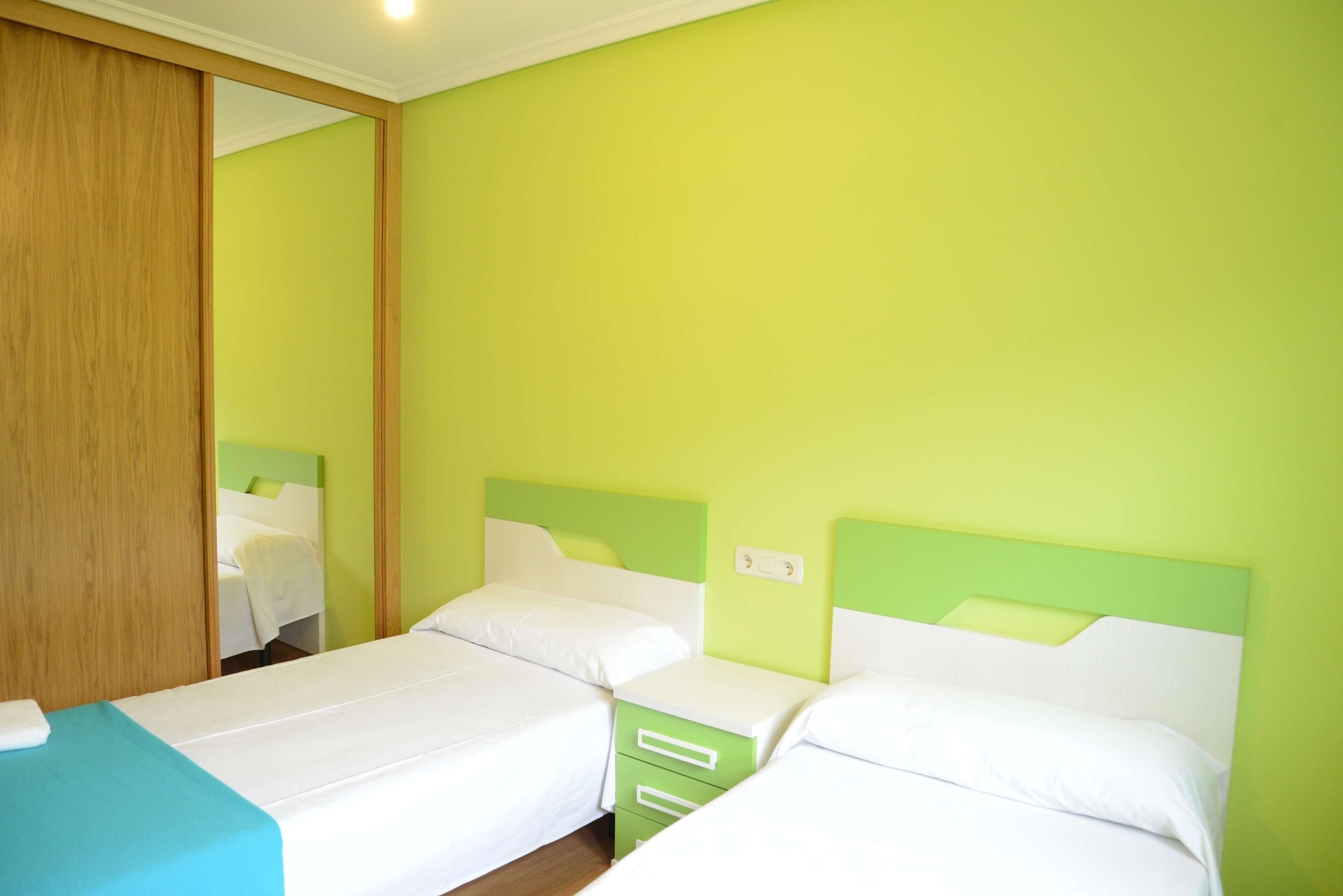 Una habitación de hotel con dos camas, un armario de madera y un espejo.