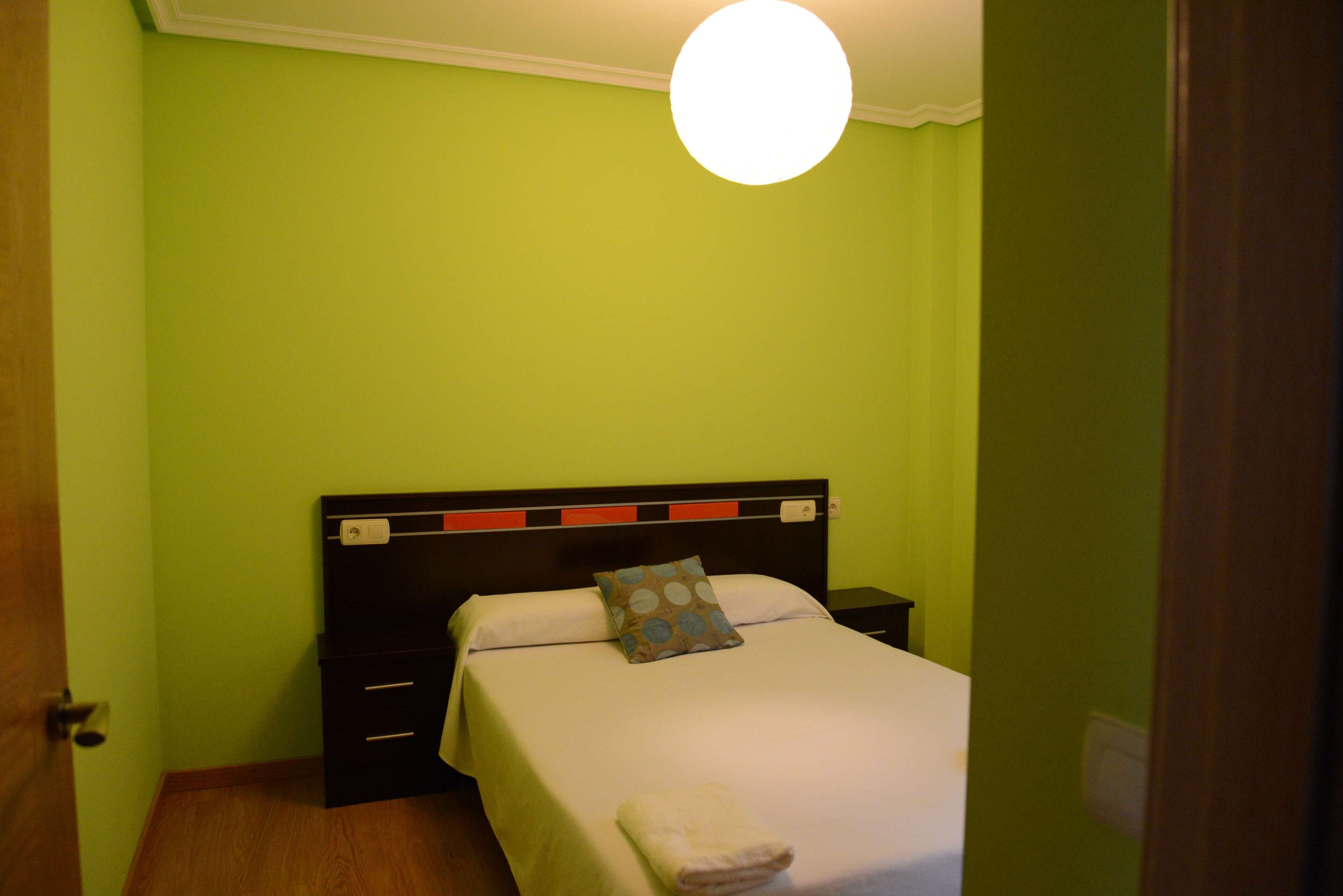 Una habitación con una cama, una mesita de noche y un enchufe.