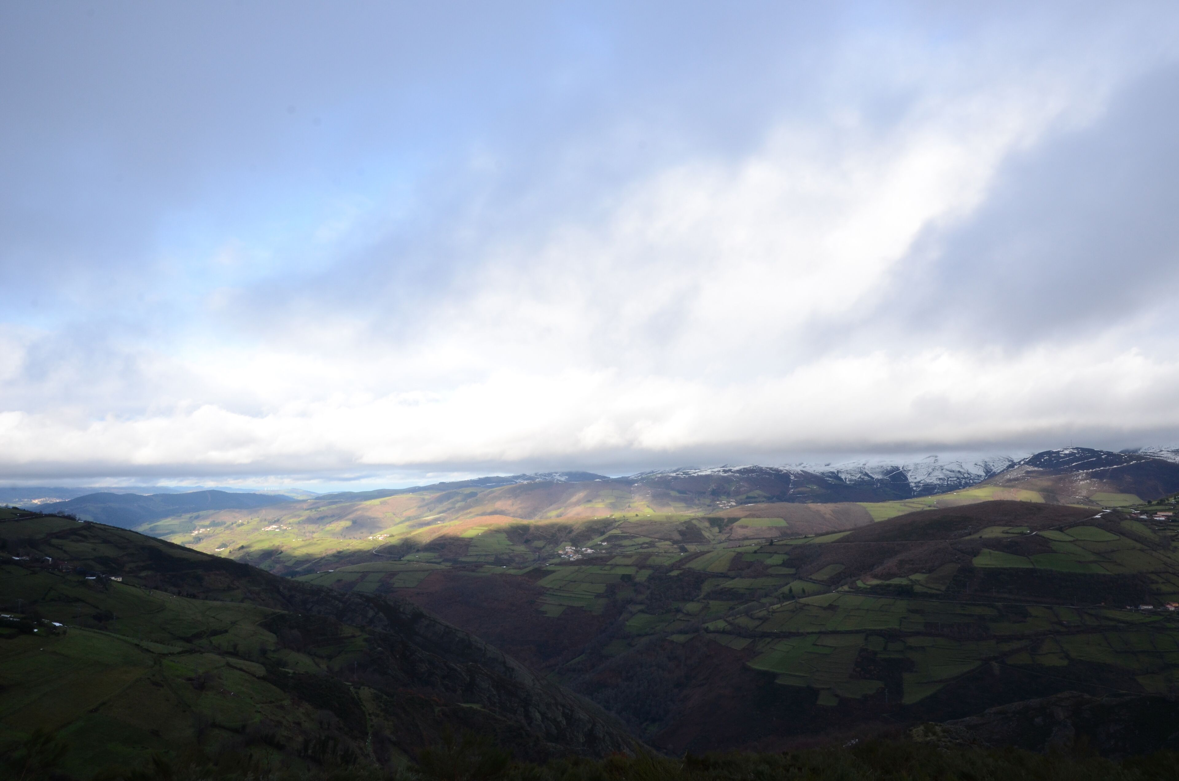 A panoramic view of a valley with rolling hills and a distant mountain range.