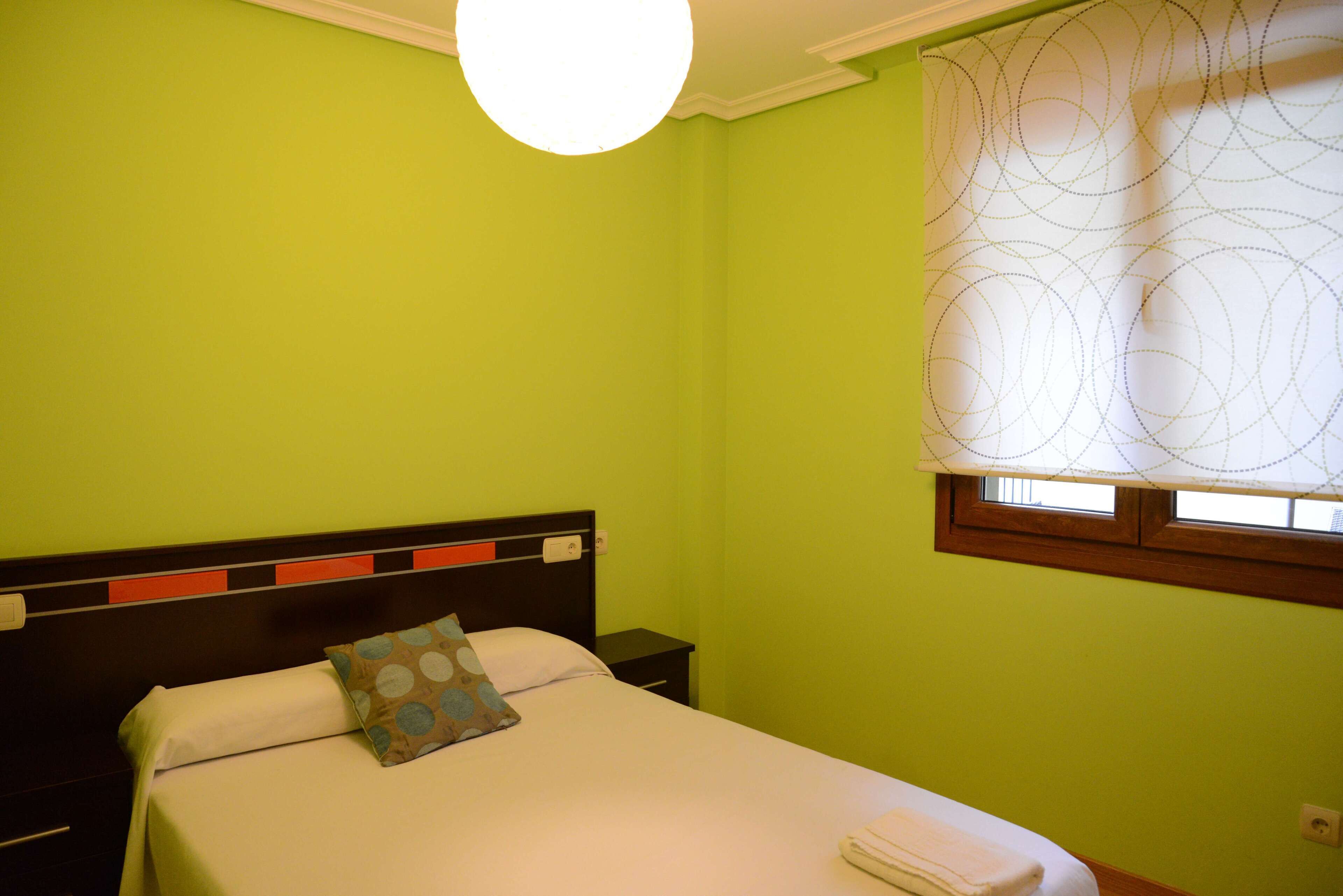 Une chambre avec un lit, une table de chevet et une fenêtre avec un rideau.