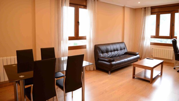 Uma sala de estar moderna com um sofá de couro, uma mesa de jantar de vidro e cadeiras pretas.