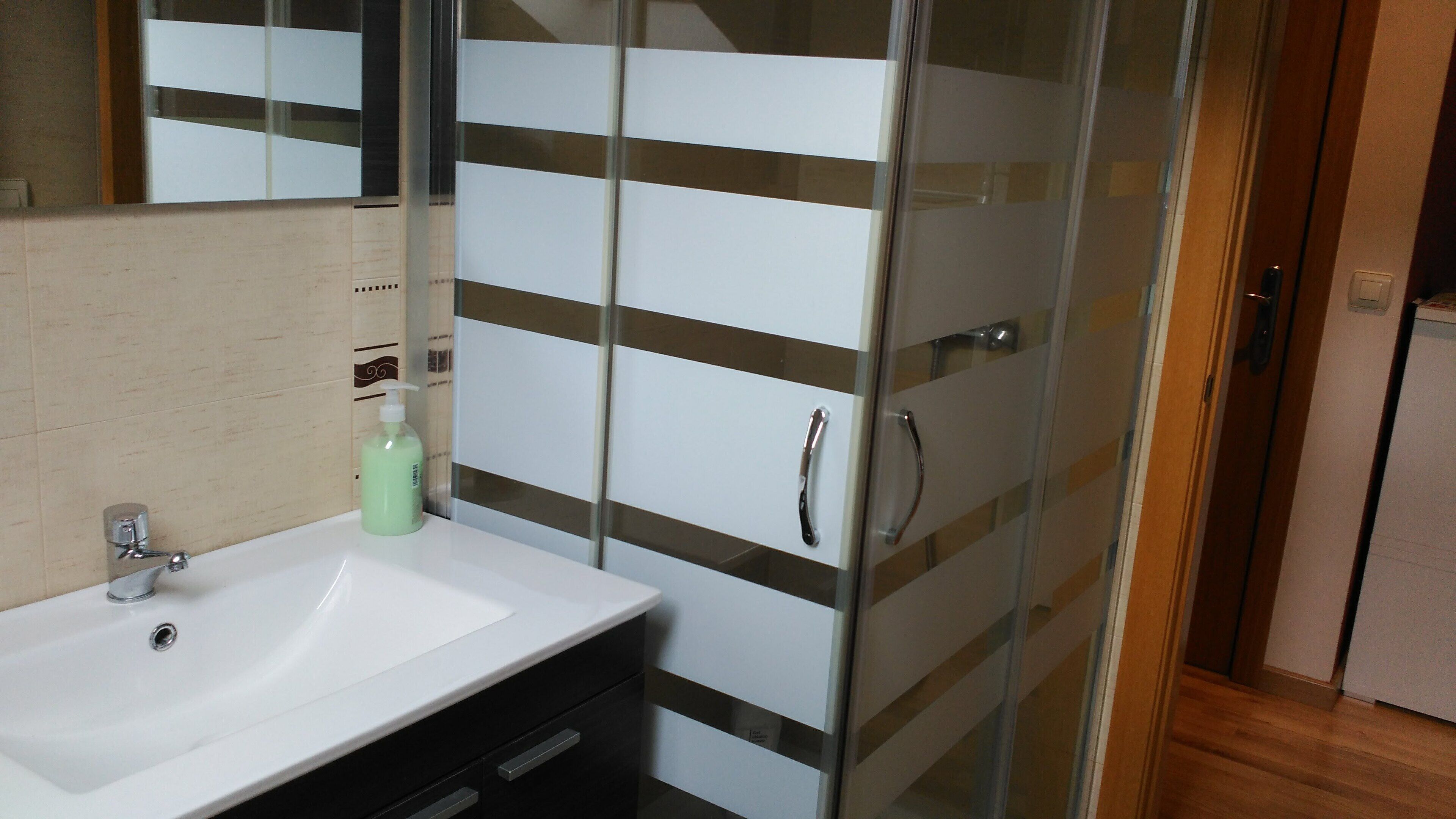 A bathroom with a white sink, a glass shower enclosure, and a mirror.