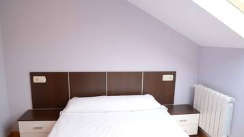 Ein Schlafzimmer mit Bett, Nachttisch, Kommode und Heizkörper.