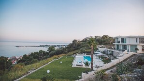 Une villa moderne dotée d’une piscine, offrant une vue sur la mer et entourée d’un jardin luxuriant.