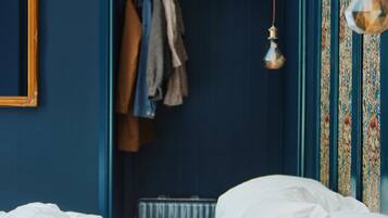 A bedroom with a bed, a hanging light fixture, a wardrobe, and a patterned wall.