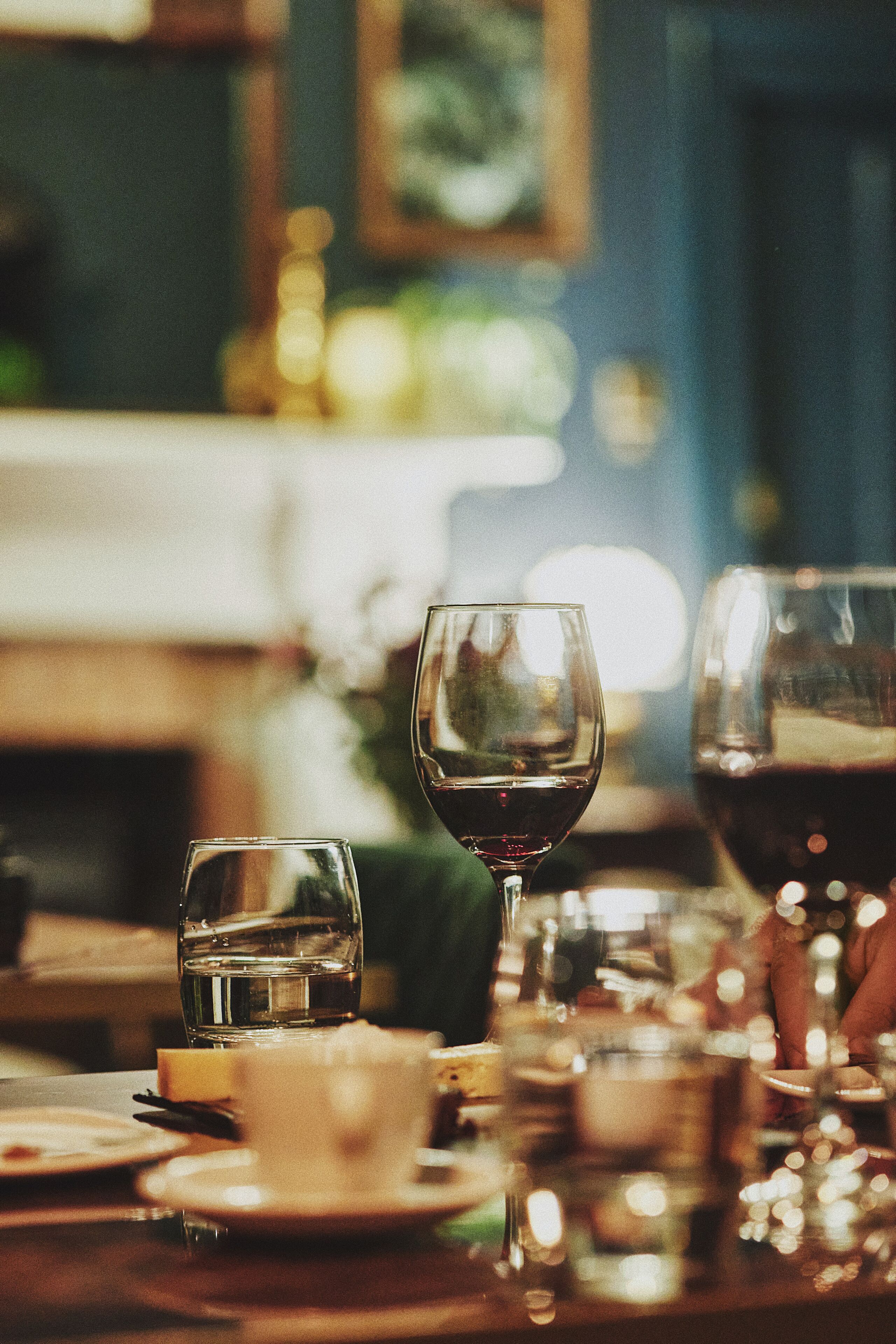 Mesa de jantar com copos e pratos diversos, sugerindo um ambiente de restaurante.