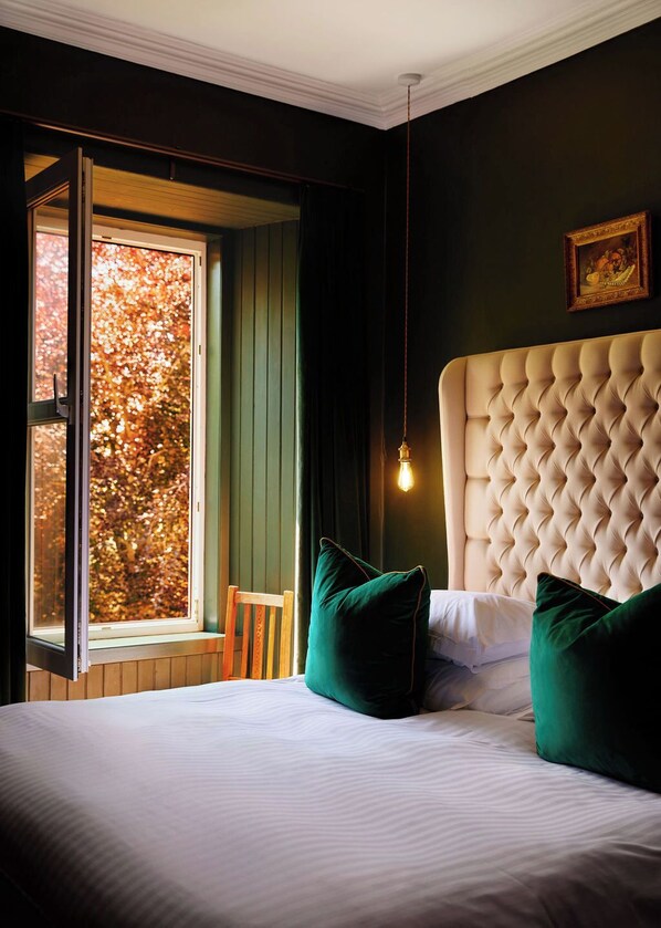 A bedroom with a large window, a tufted headboard, and green pillows. - Foyers Lodge (Inverness)