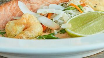A plate with a piece of salmon, shredded vegetables, and a lime wedge.